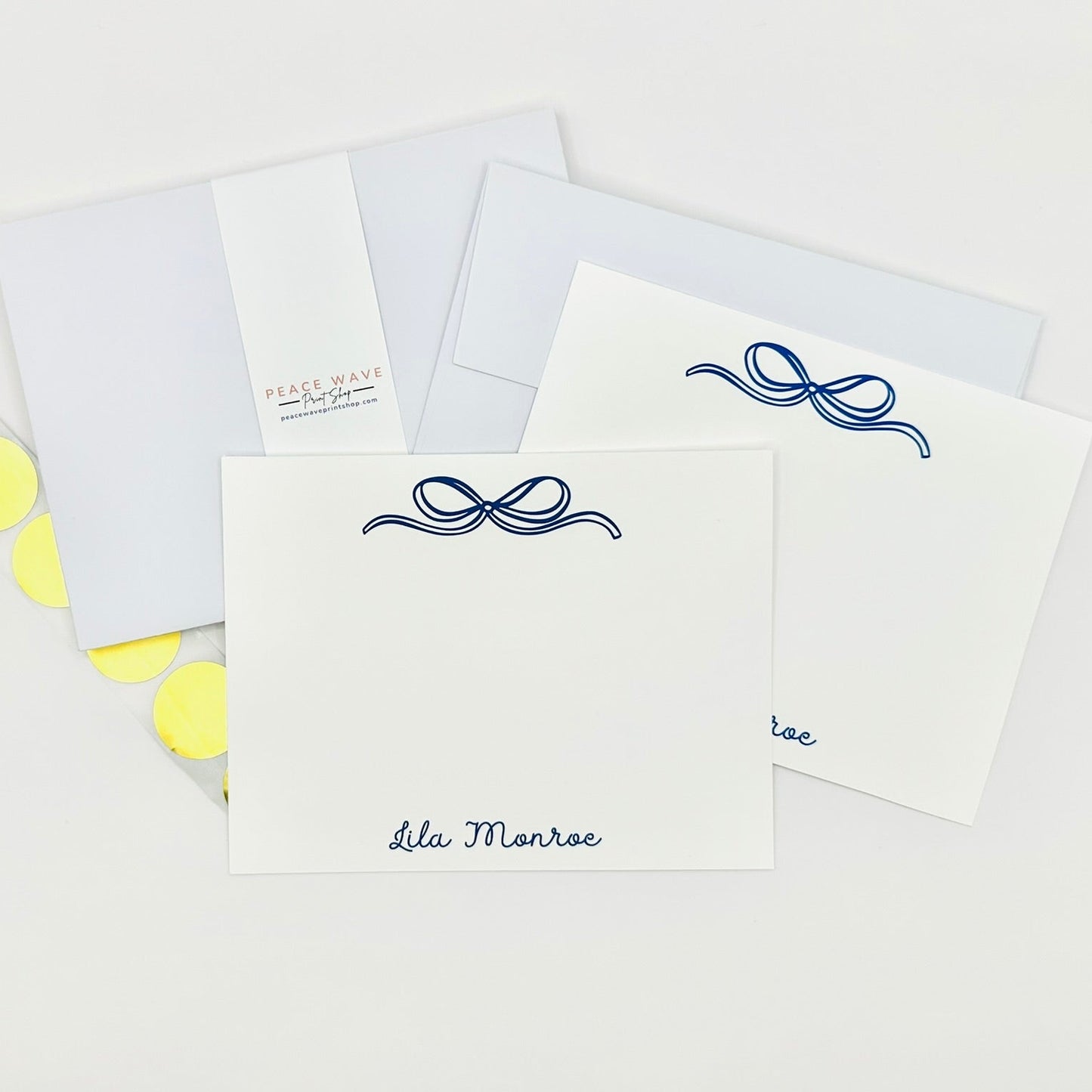 Set of personalized stationery white cards with blue decorative bows and coordinating envelopes on a white background