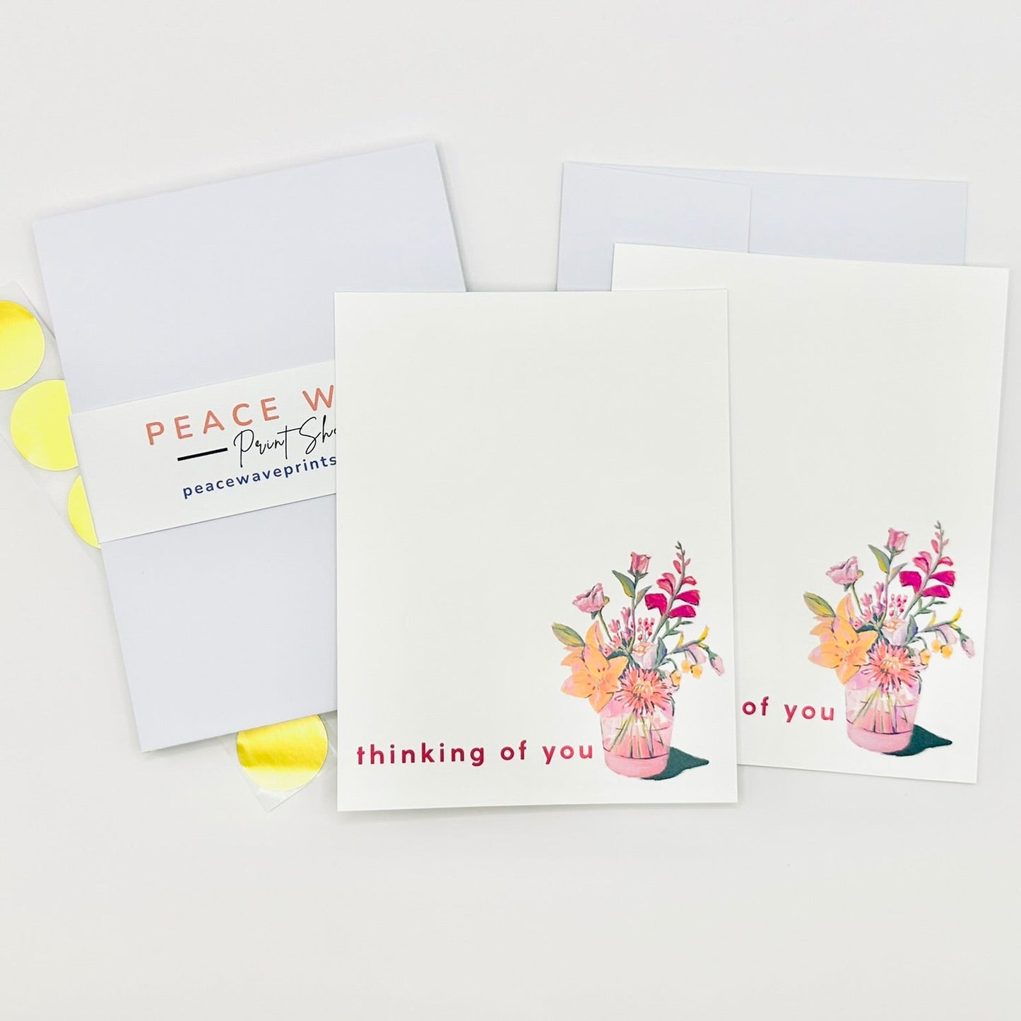 Flat stationery greeting cards with floral designs and 'thinking of you' text on a white background with envelopes and gold sticker seals