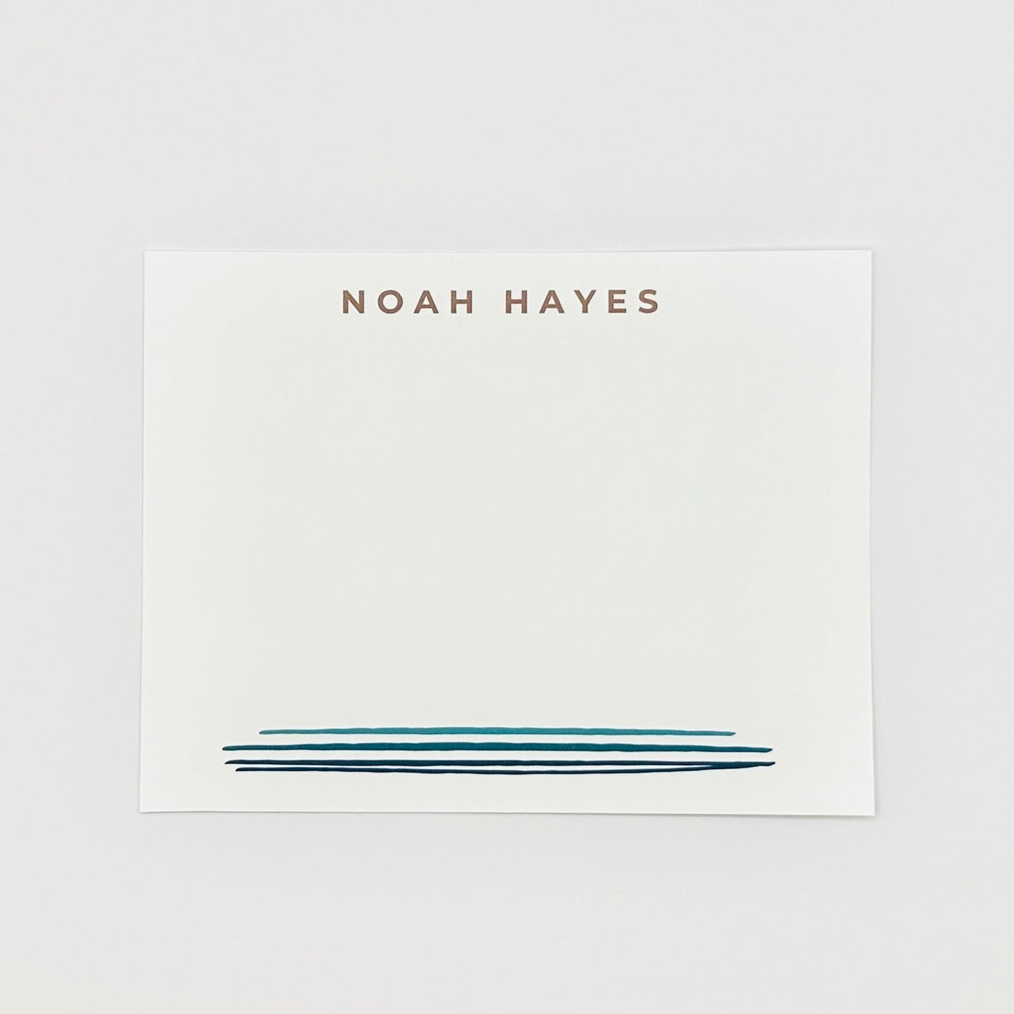 Personalized stationery note card with 'NOAH HAYES' printed on a white background and blue watercolor line design