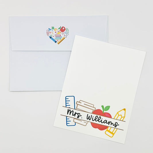 Personalized stationery note card with 'Mrs. Williams' design for classroom teacher with ruler, apple, pencil, and coffee cup and matching envelope on a white background